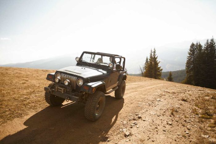 A rugged four-wheel drive Jeep parked at the peak of a mountain.