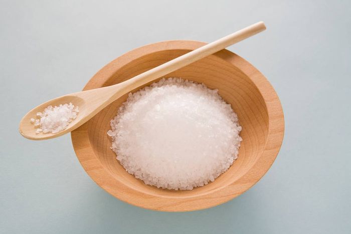 A wooden bowl filled with salt and a spoon