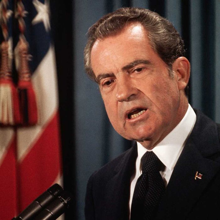 Richard Nixon speaking into a microphone with the American flag in the background