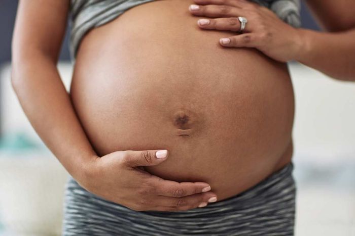 A woman holding her pregnant belly, cropped shot