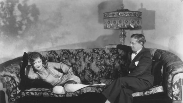 In 1928, Clara Bow is seen lounging on the sofa in her Beverly Hills residence, accompanied by her father, Robert Bow.
