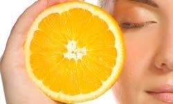 Woman holding an orange near her face.