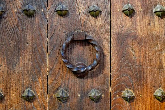 A doornail and door knocker are pictured as symbols of something lifeless.