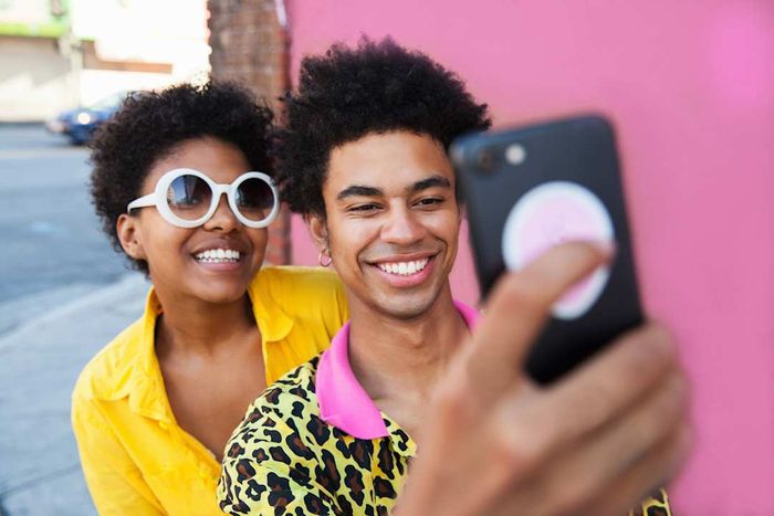 Two individuals capturing a selfie using a phone