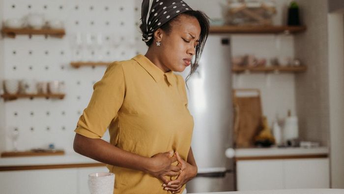 A woman experiencing discomfort from abdominal pain.