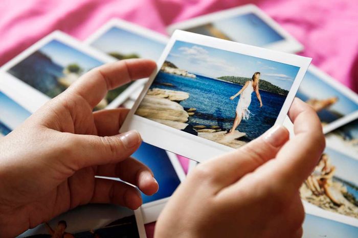 photo of a woman holding a collection of polaroid pictures