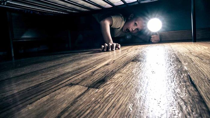 photo of a frightened child peering under their bed