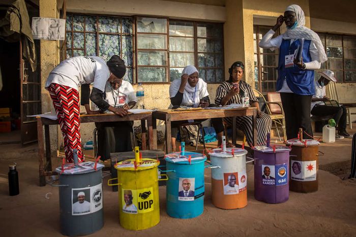 In Gambia, voters use marbles to vote by dropping them into color-coded buckets featuring candidates' photos.