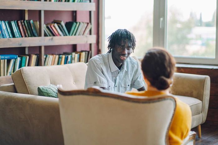 A young man sitting on a couch in a therapist’s office