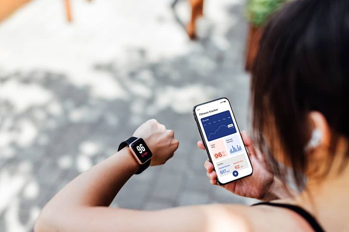 photo of a woman reviewing a fitness tracking app and watch after exercising