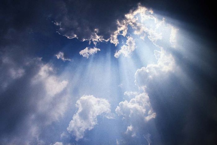 A blue sky adorned with clouds and sunbeams