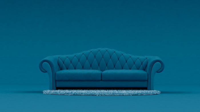 A blue couch against a blue backdrop