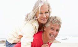 Elderly Man Carrying Woman on His Back at a Snowy Beach