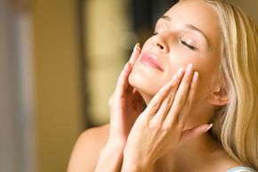 A woman gently applying moisturizer to her face