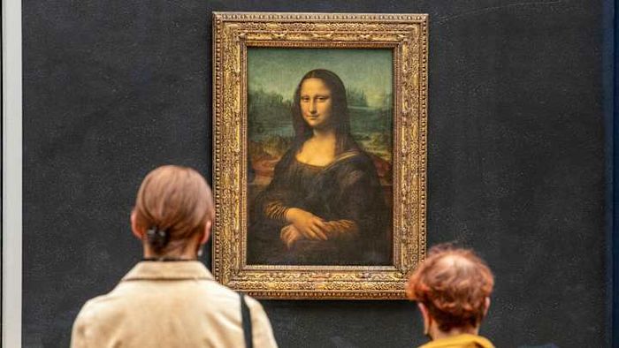 Tourists at the Louvre gazing at the iconic 'Mona Lisa.'