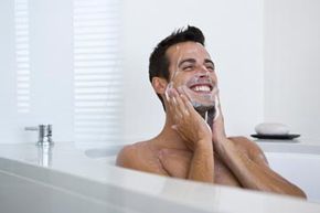 A man in a tub gently cleanses his face.