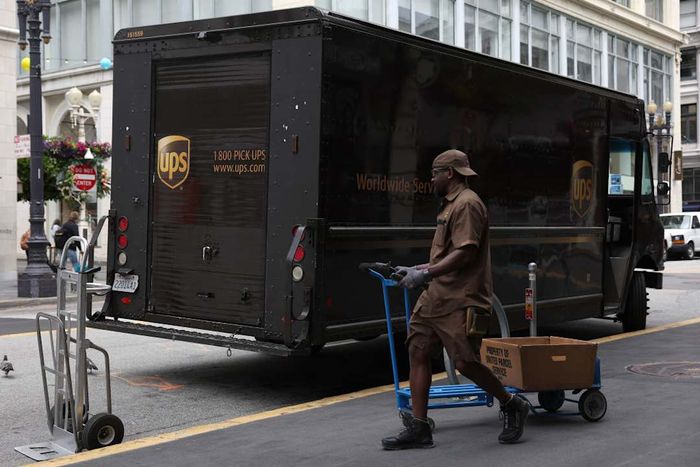 A UPS delivery driver standing outside a UPS truck.