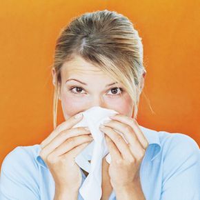 woman using tissue to blow her nose