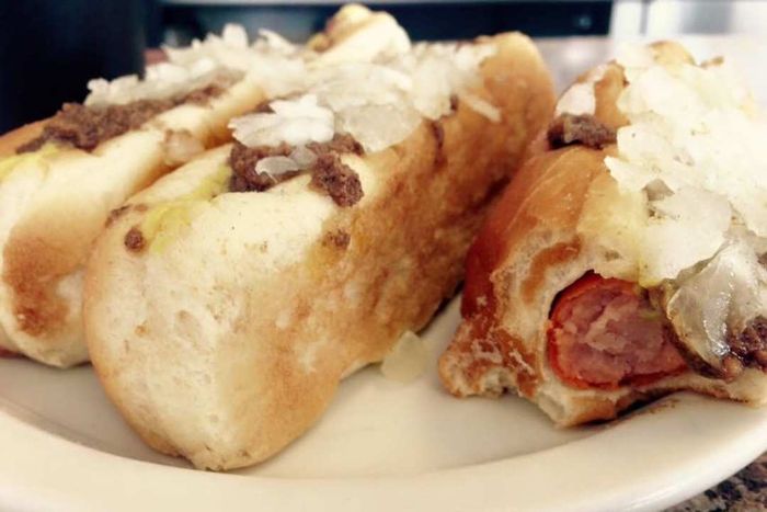 Three hot dogs topped with onions and ground beef
