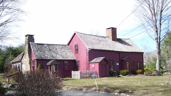 A red house featuring a chimney that runs down one side.