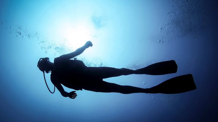 A silhouetted scuba diver