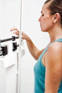 A woman weighing herself on a scale