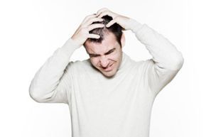 A man experiencing frustration while scratching his head