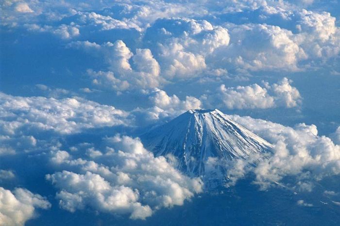 The summit of Mount Fuji emerging through a blanket of clouds.