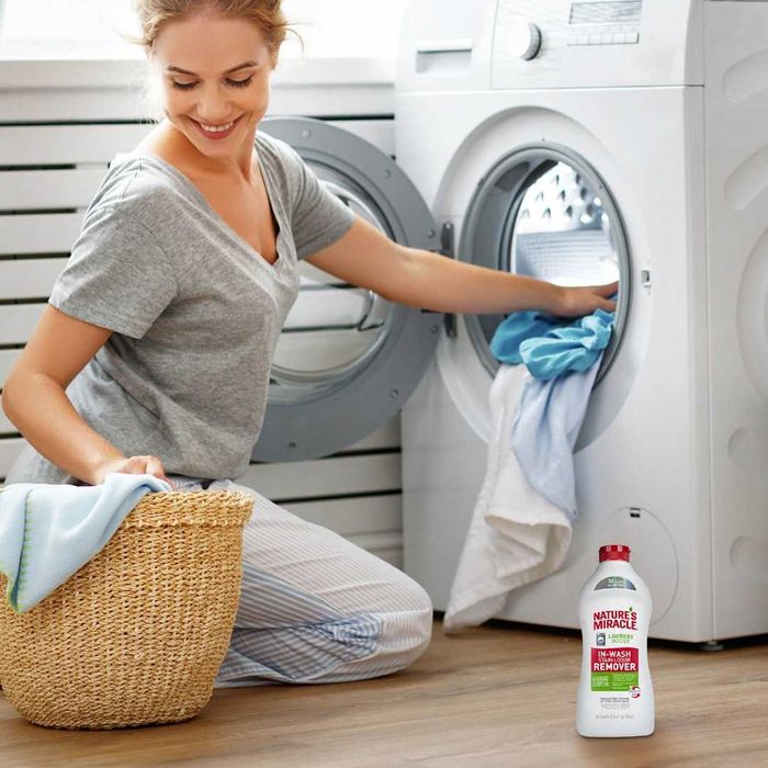 A woman doing laundry with Nature's Miracle Laundry Boost In-Wash Dog Stain and Odor Remover.