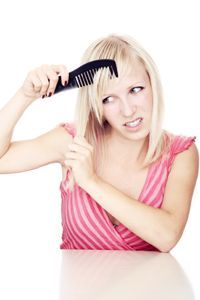 A woman feeling frustrated while combing her hair