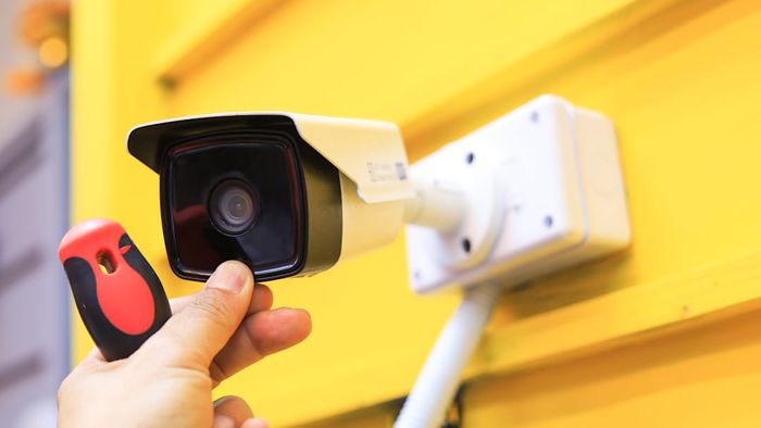 A man mounting a security camera on the exterior of a building.