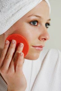 A woman holding an exfoliating pad to her face.