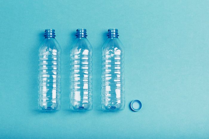 Three plastic bottles resting on a blue backdrop