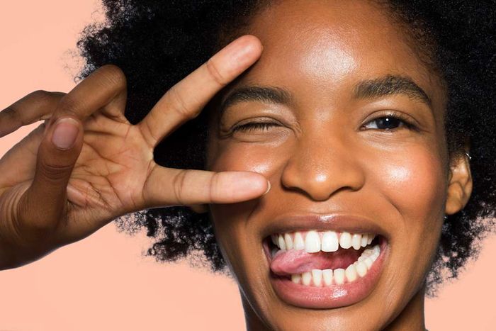 A woman winking while making a peace sign