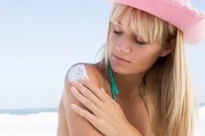 A woman applying sunscreen for sun protection.