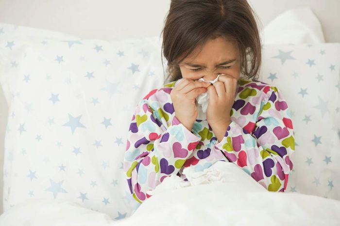 A young girl blowing her nose