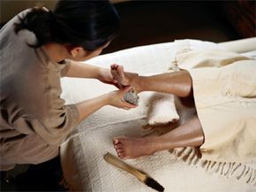 A man using a pumice stone to exfoliate someone's foot.