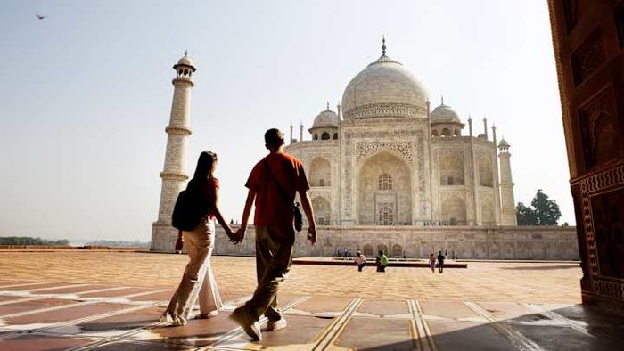 A pair strolling through the serene courtyard of the Taj Mahal.