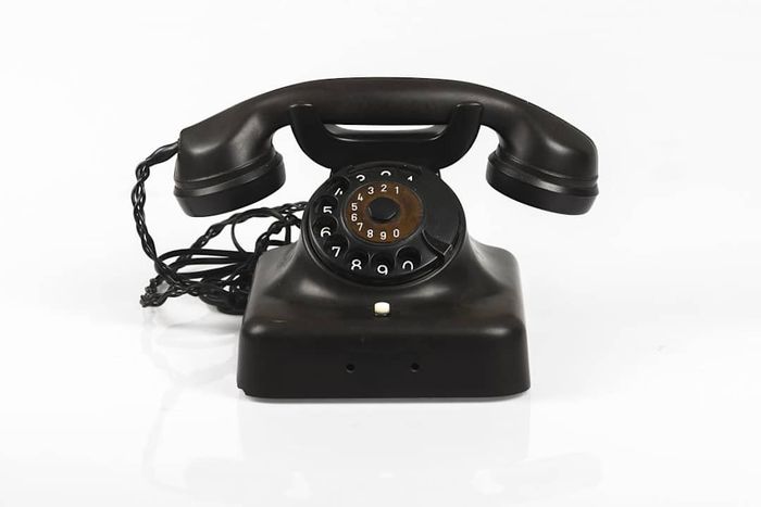 A retro telephone resting on a white background