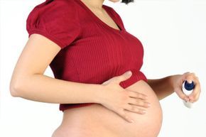 A pregnant woman using a spray to treat her stretch marks