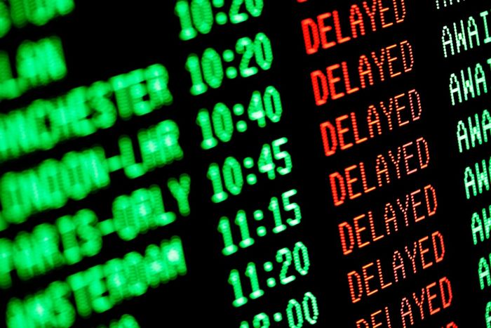 An airport departure board displaying multiple flights marked as DELAYED