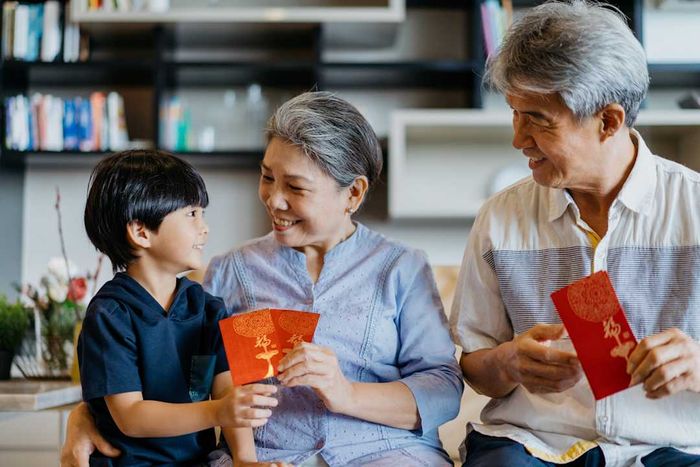Chinese grandparents presenting a red envelope (angpao) to their grandchild during Chinese New Year celebrations.