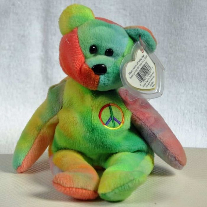 A tie-dyed bear featuring a peace sign on its chest, set against a white background.