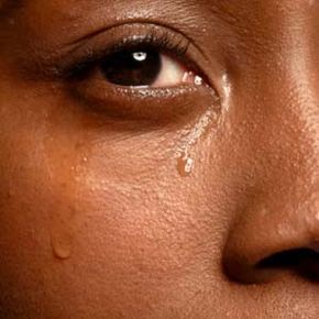 A detailed view of a tear rolling down a woman's face.