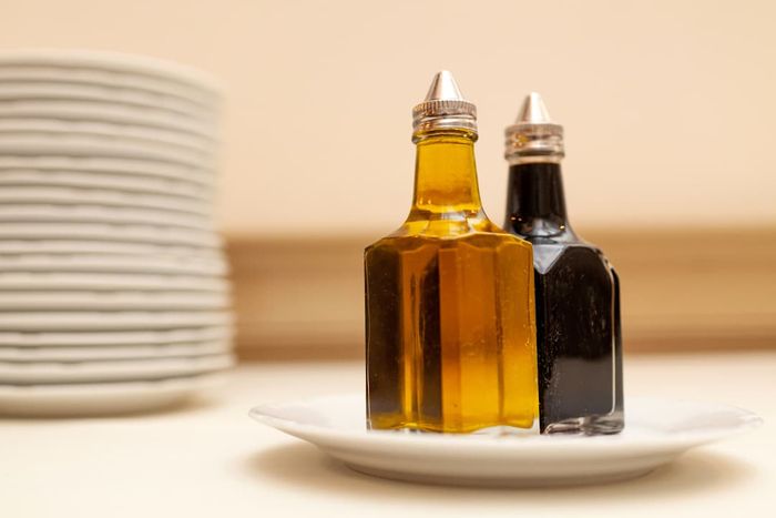 Two bottles of oil and vinegar sitting on a table