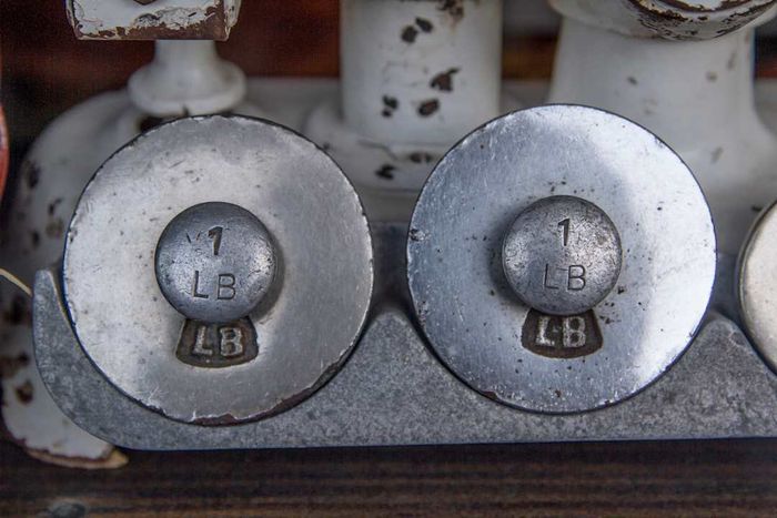 An antique scale featuring two 1-pound weights.