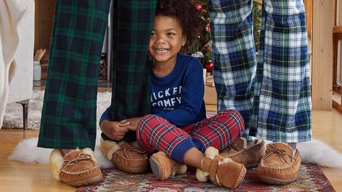 A child wearing Wicked Good Slippers from L.L.Bean, with two adults also sporting the same cozy footwear.