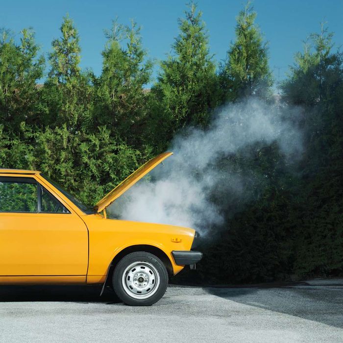 A yellow car emitting smoke from its hood.