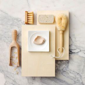 A top-down view of various exfoliating products arranged on a marble surface.