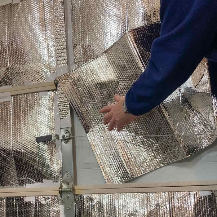 A person adding reflective foil insulation to their garage.